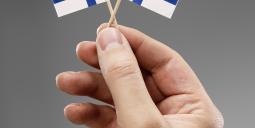 Två finska flaggor i en hand. Foto: Colourbox