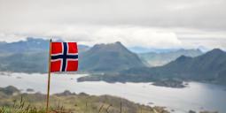 Norska flaggan med fjord i bakgrunden. Foto: Colourbox